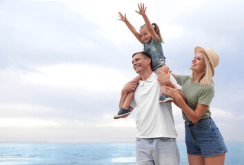 Happy family spending time together near sea on sunny summer day