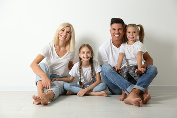 Happy family sitting on floor near white wall