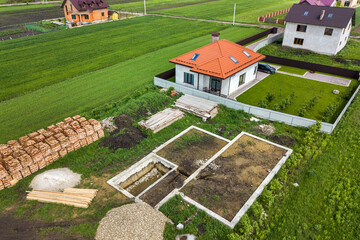Aerial view of building site for future brick house, concrete foundation floor and stacks of yellow...