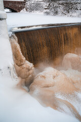 Frozen foam from steaming water flowing through a dam in freezing temperature