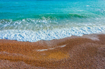A sea wave runs over a pebble beach .