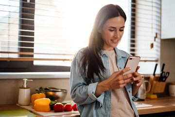 Smiling attractive young woman texting on mobile phone