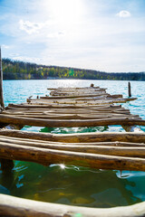 Fototapeta premium Wooden masonry stands on the water isolated. Entry into the lake from a wooden bridge into the lake
