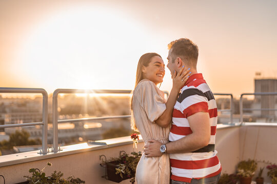 Beautiful young couple just engaged on rooftop of building with beautiful view. Boyfriend and girlfriend on rooftop hugging. Love concept 