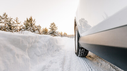 Close-up of car tires in winter on a forest road covered with snow