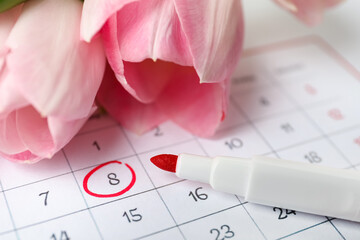 Tulips and red marker on calendar near date 8th of March, closeup. International Women's Day