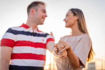 Beautiful couple engaging on rooftop. Man on his knee asking his girlfriend to merry him. Love and beauty. Engagement on roof top with beautiful view