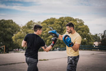 Two men boxing outdoors. Sparring training outside in city