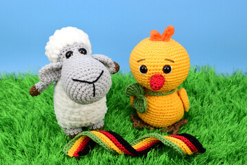 Easter lamb and chicken, knitted from thick yarn. In the foreground is an Easter ribbon.
