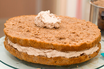 Working process of baking cake at home. Close up of chocolate biscuit sliced with cream. Culinary and delicious dessert concept.