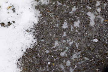 Abstract background. Blue ice with air bubbles and white snow, frozen lake or puddle water surface on cold winter day.