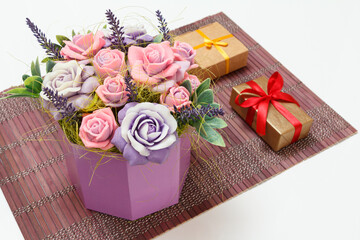 Bouquet of soap in form of roses and gift boxes on bamboo napkin.