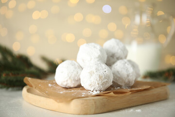 Fototapeta na wymiar Christmas snowball cookies and fir tree branches on light table, closeup