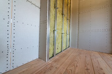 Wall of a room under renovation with mineral rock wool insulation and metal frame prepared for...