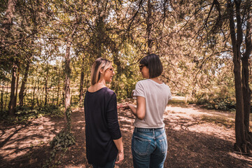 Two happy young women having coffee break together in park