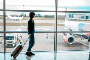 Woman on airport with bag waiting for plane 