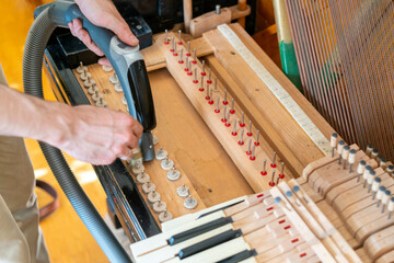 Setting up an old piano. The master repairs an old piano. Deep cleaning the piano. Hands of professional worker repairing and tuning an old piano. toned © jollier_