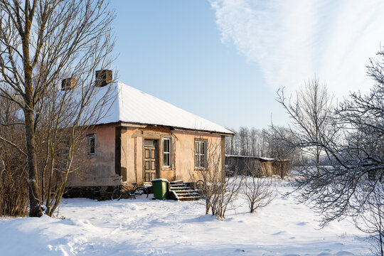a small country house in winter with an abandoned bicycle