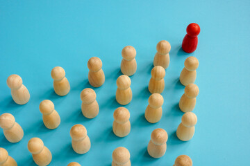 Red figurine at the head of the wooden ones. Leadership and teamwork concept.