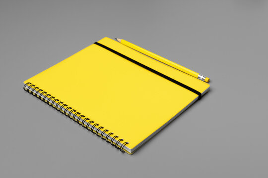 Yellow notepad with yellow pencil on gray background