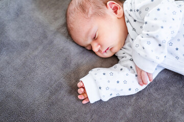 Smiling baby girl lying on a bed sleeping on blue sheets