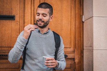 Young urban man on break from work drinking coffee and eating cookie 