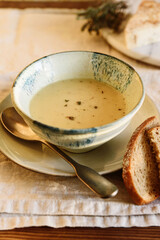 Cheese cream soup in bowl on beige linen table. Selective focus