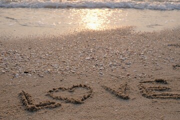 Handwritten love words on the beach sand