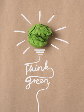 Recycled paper background with green crumpled paper ball as light bulb, ecology concept, innovations, renewable energies