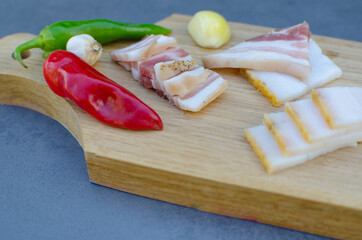 Raw pork lard with meat, colorful peppers and garlic on a gray background for copy space. A large...