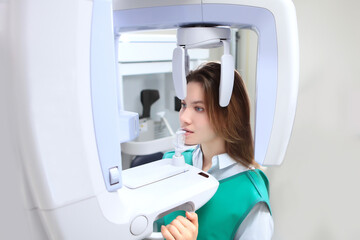 The girl in the X-ray room makes a panoramic picture of her teeth. Disease prevention and dental treatment. X-ray equipment. Panoramic image of teeth. Modern dentistry and medicine.