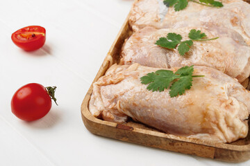 Raw marinated chicken breasts on wooden board