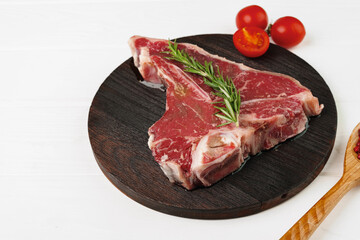 Raw t-bone steak on wooden cutting board on wooden table