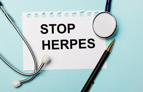 On a light blue background, a stethoscope, a pen and a sheet of paper with the inscription STOP HERPES. Medical concept