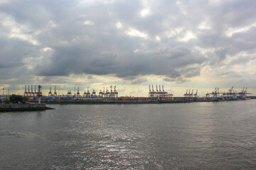 Dramatischer Himmel &uuml;ber viele Kr&auml;ne an Hafen