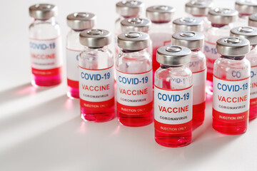 Many vaccine glass bottles for vaccination against COVID-19 SARS-CoV-2 coronavirus pandemic on white background