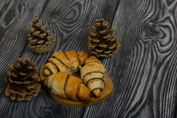 Cinnamon croissants. Rich pastries. Nearby pine cones. Close-up shot.