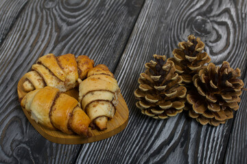 Cinnamon croissants. Rich pastries. Nearby pine cones. Close-up shot.