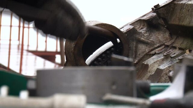 A man in gloves works with a crowbar on the street. Metal device