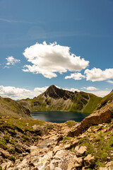 Fanealm und Wilder See in Suedtirol, Italy, Alpine pastures with a deep blue lake, green meadows and a blue sky with fleecy clouds, in summer