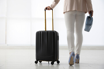Businesswoman with black travel suitcase in airport