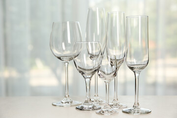 Different elegant empty glasses on grey table indoors