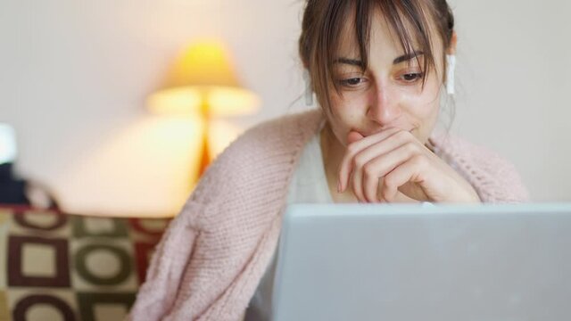 front view young woman with wireless earphones and laptop talking with someone. woman have online conversation from cozy home