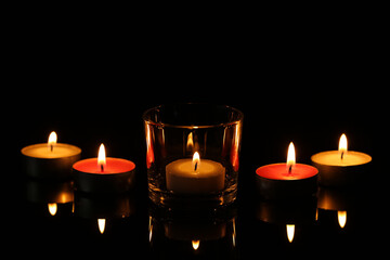 Burning small wax candles in darkness. Funeral symbol