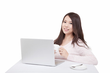 Portrait of young sitting in front of laptop holding coffee cup 