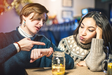 Two disgruntled women are tired of waiting for their order in a restaurant or bar and point to the...