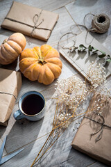 Packaged and bandaged gifts, pumpkins, a cup of tea and dried plants are on the table. Preparing for the birthday.