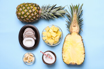 Fototapeta na wymiar Flat lay composition with pineapples and coconuts on light blue background