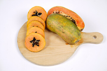 Whole Papaya fruit with a few slices isolated on a bright background. Close-up of juicy and delicious fresh papaya. Overripe papaya that starts to rot will give off a sweet, honey-like liquid.