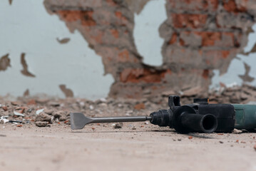 Hammer drill with chisel on the old brick wall background. Removing an old putty from the wall...